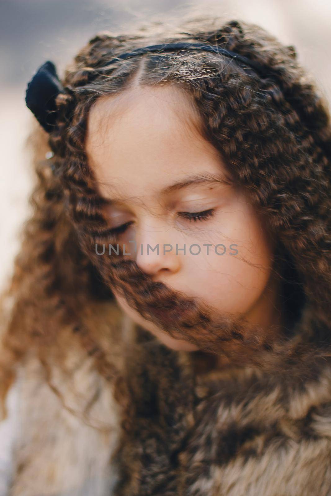 Portrait of stylish baby girl 4-5 year old wearing boots, fur coat, moving and playing. Autumn fall season.