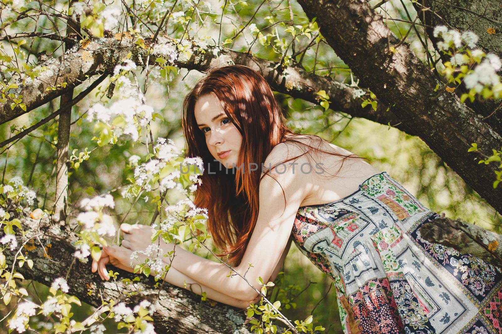Portrait of carefree young woman in boho style dress in spring cherry blossom garden.