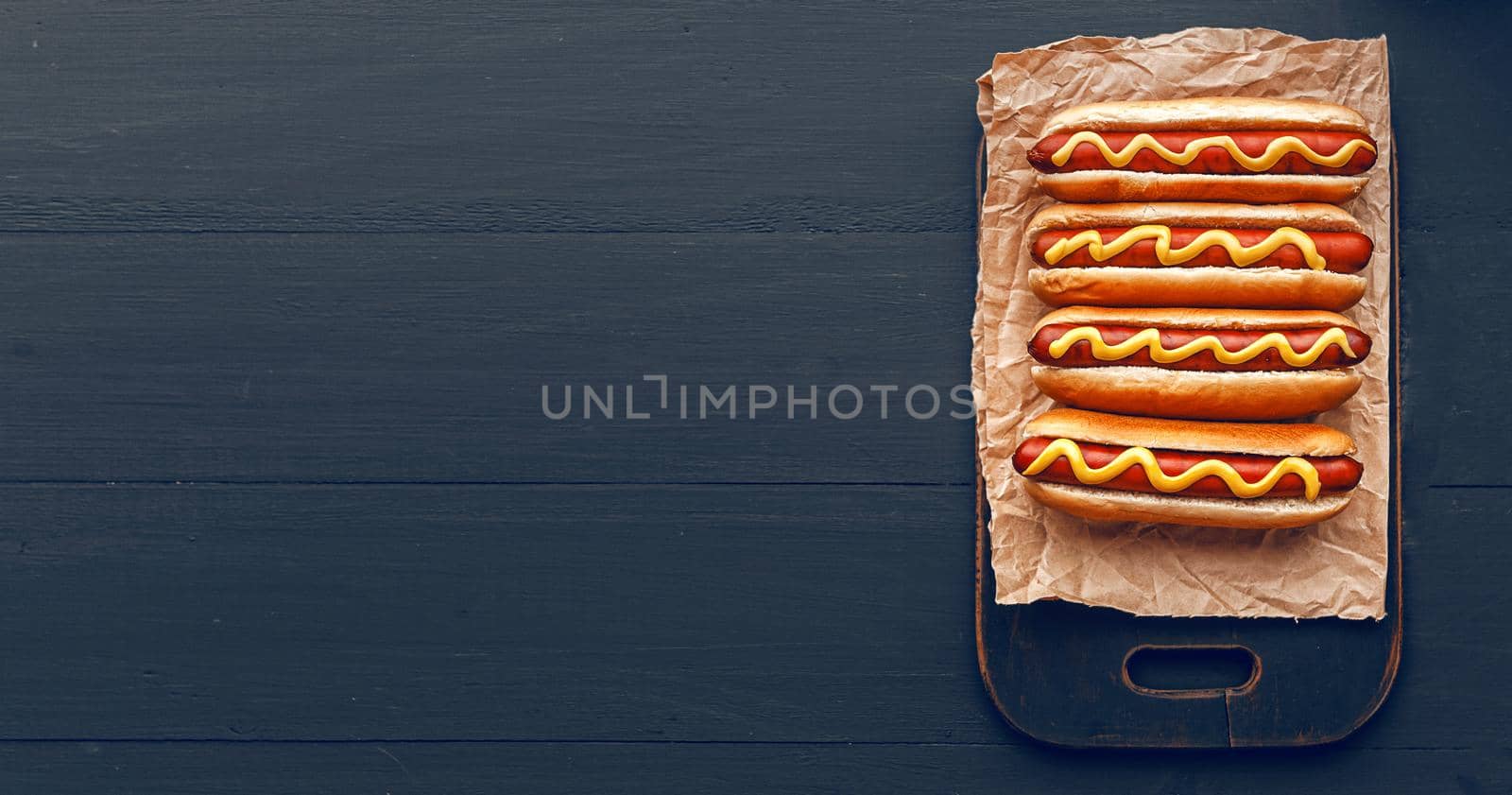 Barbecue Grilled Hot Dogs with  yellow American mustard, On a dark wooden background by vvmich