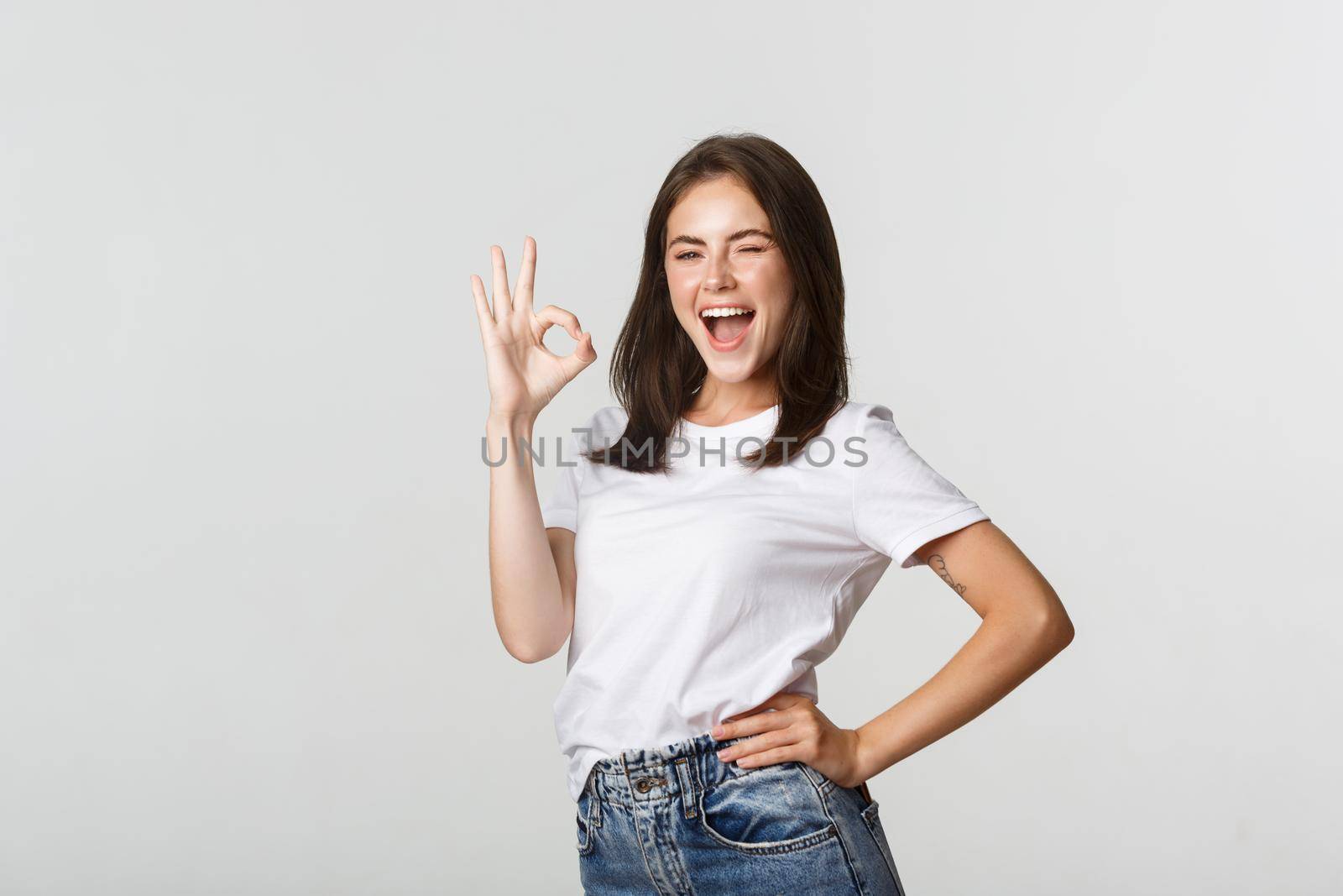 Confident and upbeat attractive girl showing thumb-up gesture in approval.