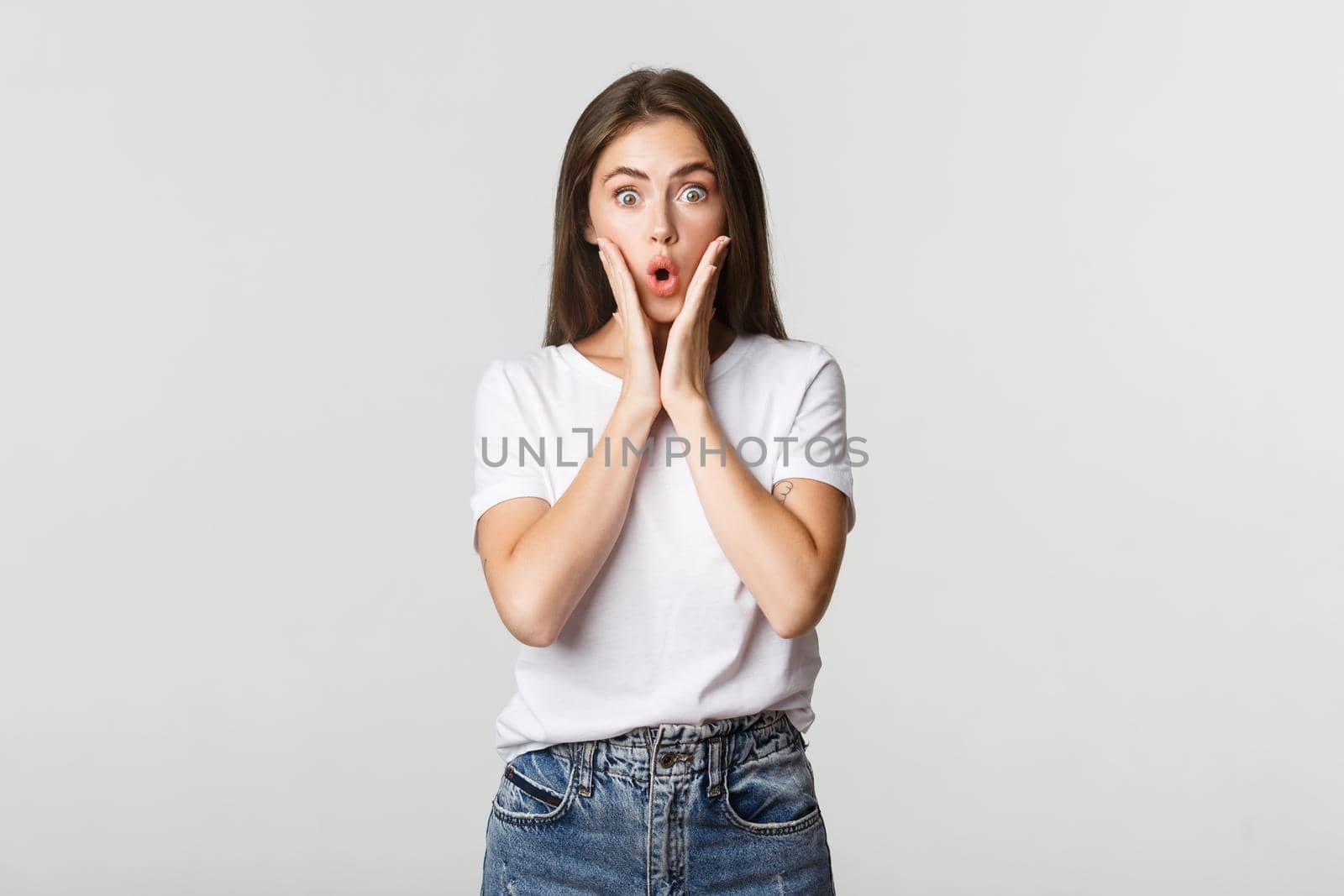 Portrait of surprised and amused brunette girl looking wondered, gasping impressed.