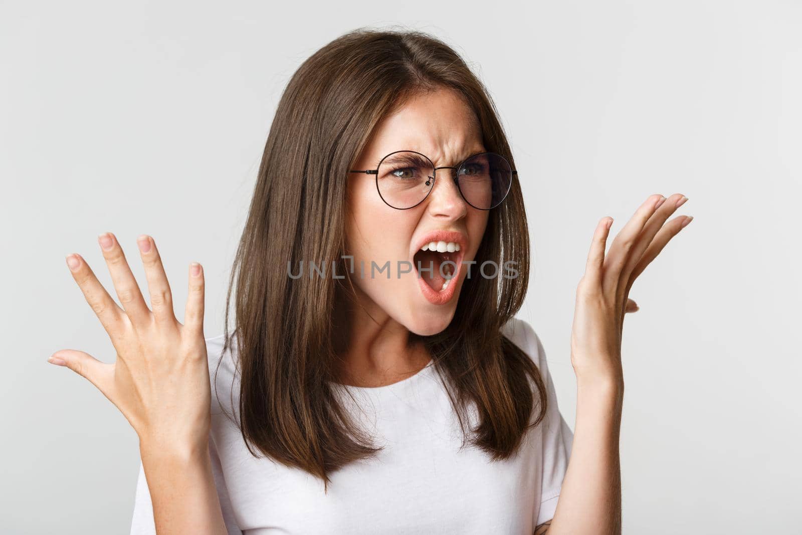 Close-up of angry and outraged beautiful woman in glasses yelling and shaking hands, having an argument.