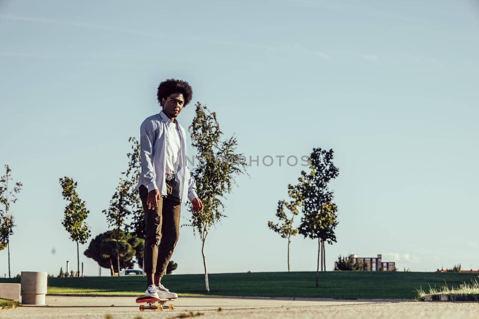 Young african american man skateboarding in modern park