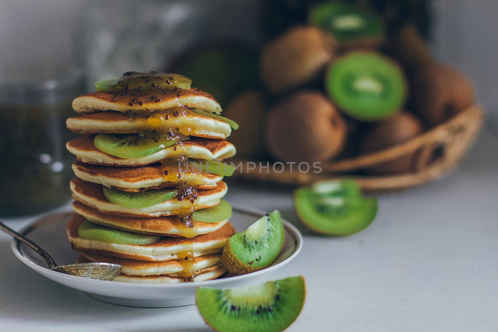 Plate of pancakes dripping with kiwi jam with kiwi pieces. Shrovetide Maslenitsa Butter Week festival meal. Shrove Tuesday. Pancake day