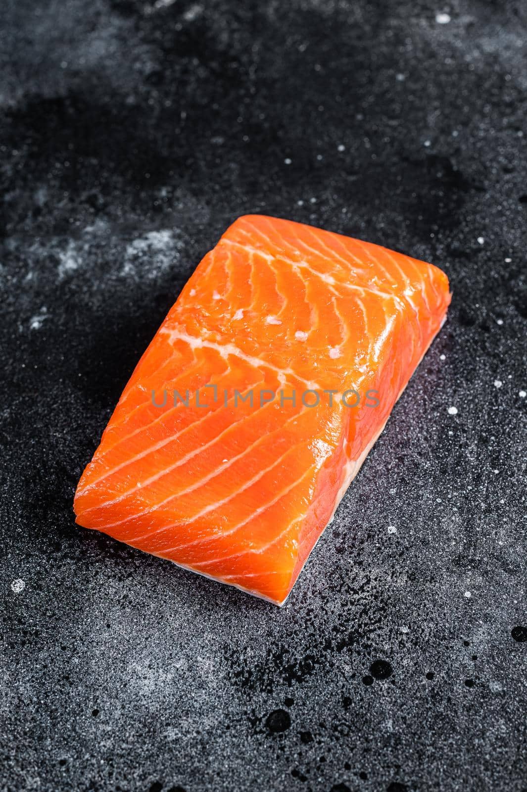 Raw salmon fillet steaks on kitchen table. Black background. Top view.