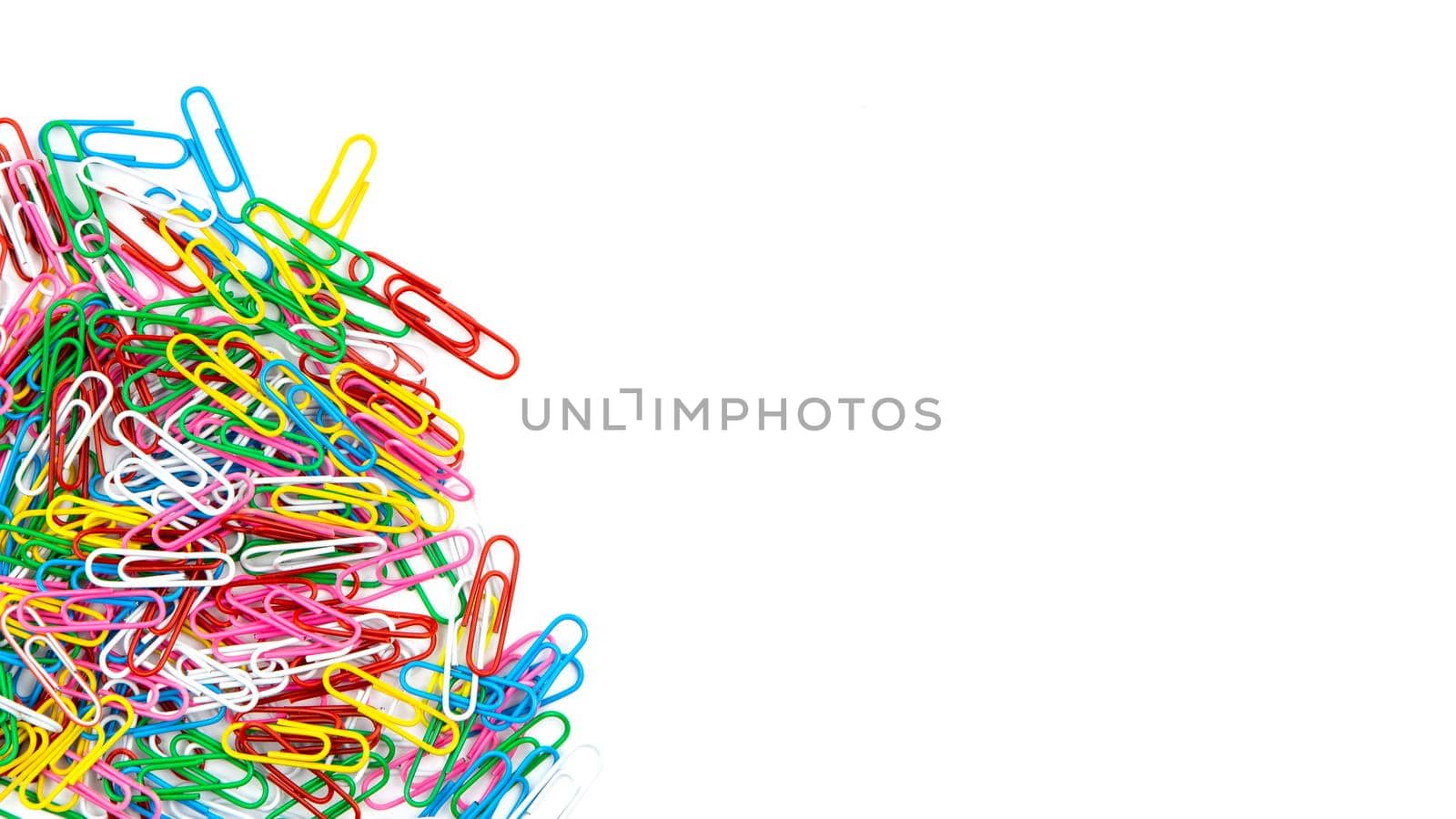 Many color stationery paper clips on a white background. Top view and copy space.