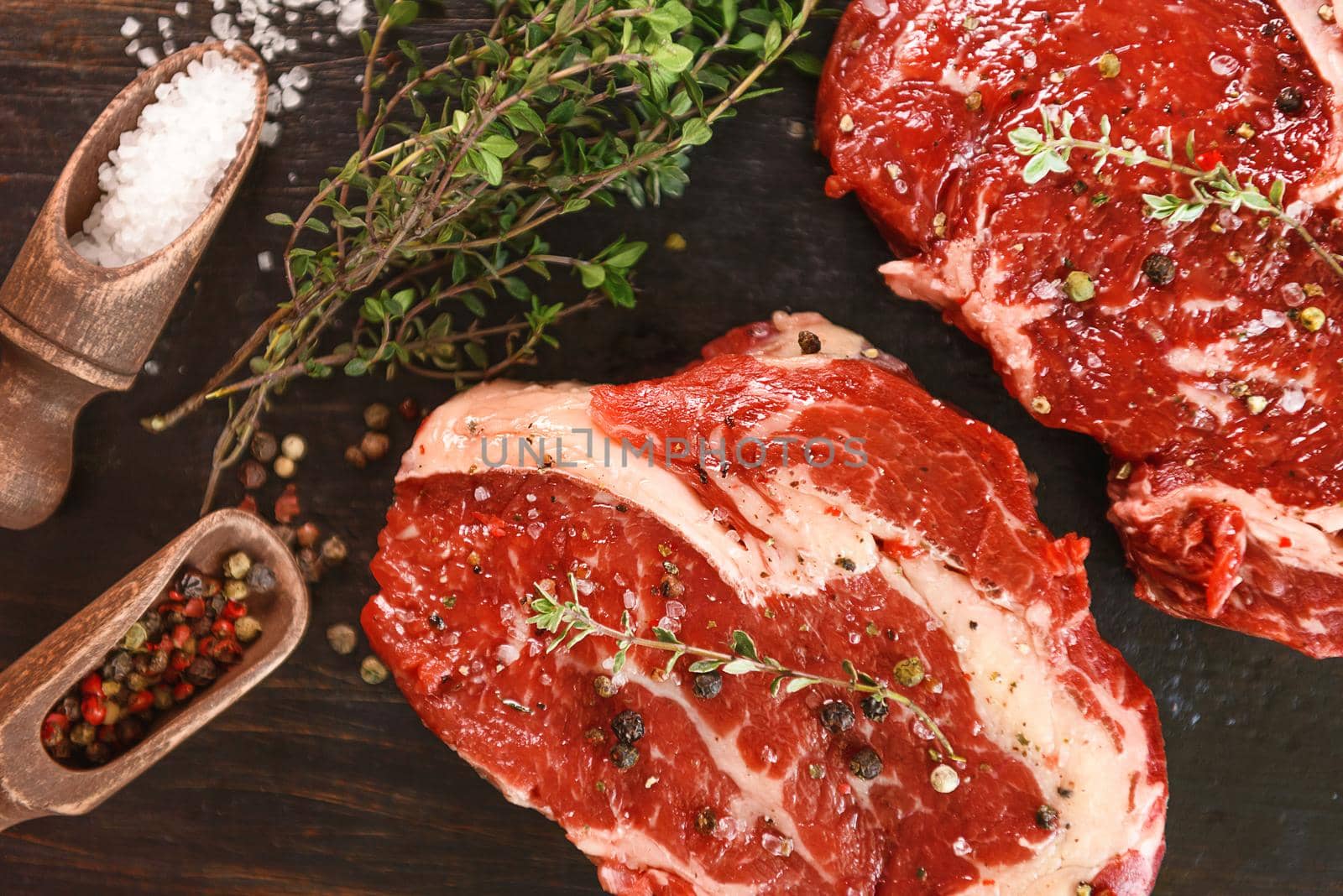 two raw marbled beef steaks in olive oil and spices ready for frying. dinner party concept