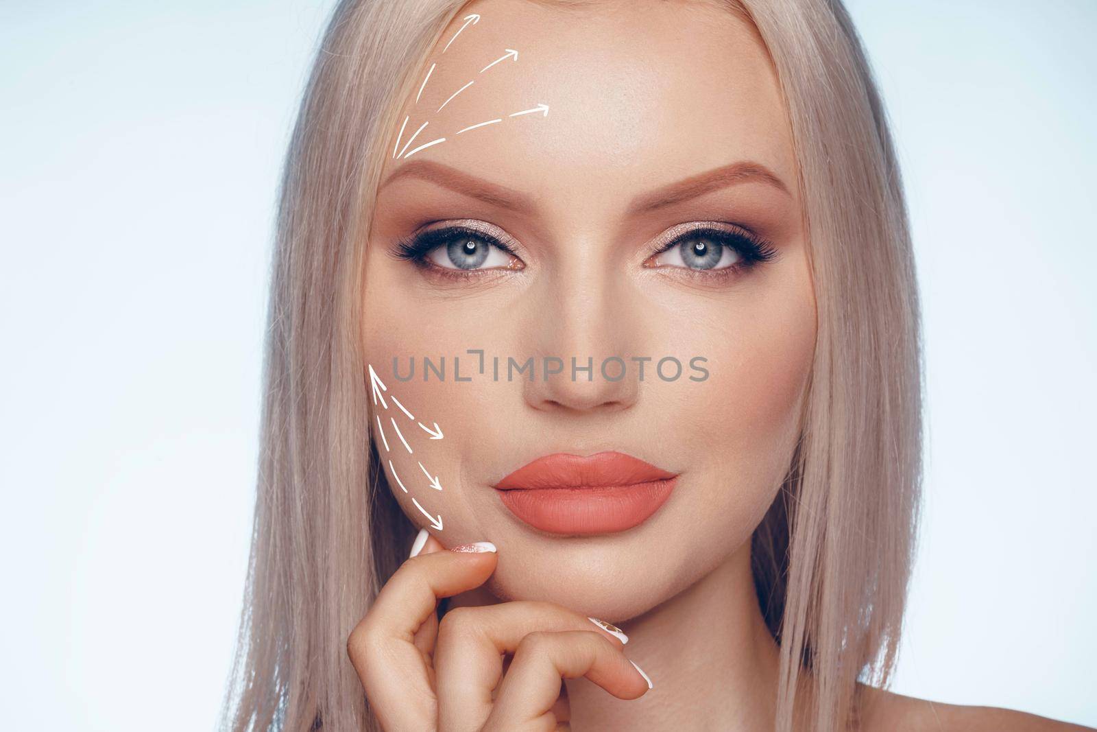 Caucasian beautiful female face marked with arrows on the main facial lifting lines, close up