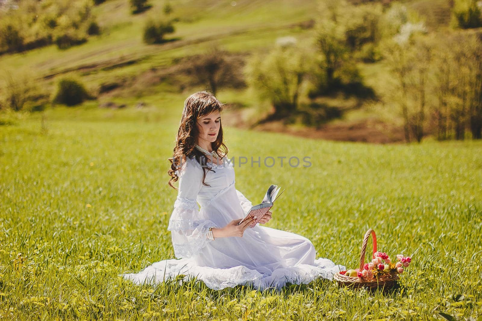 Portrait of carefree young woman in white vintage wedding style dress in spring cherry blossom garden valley.