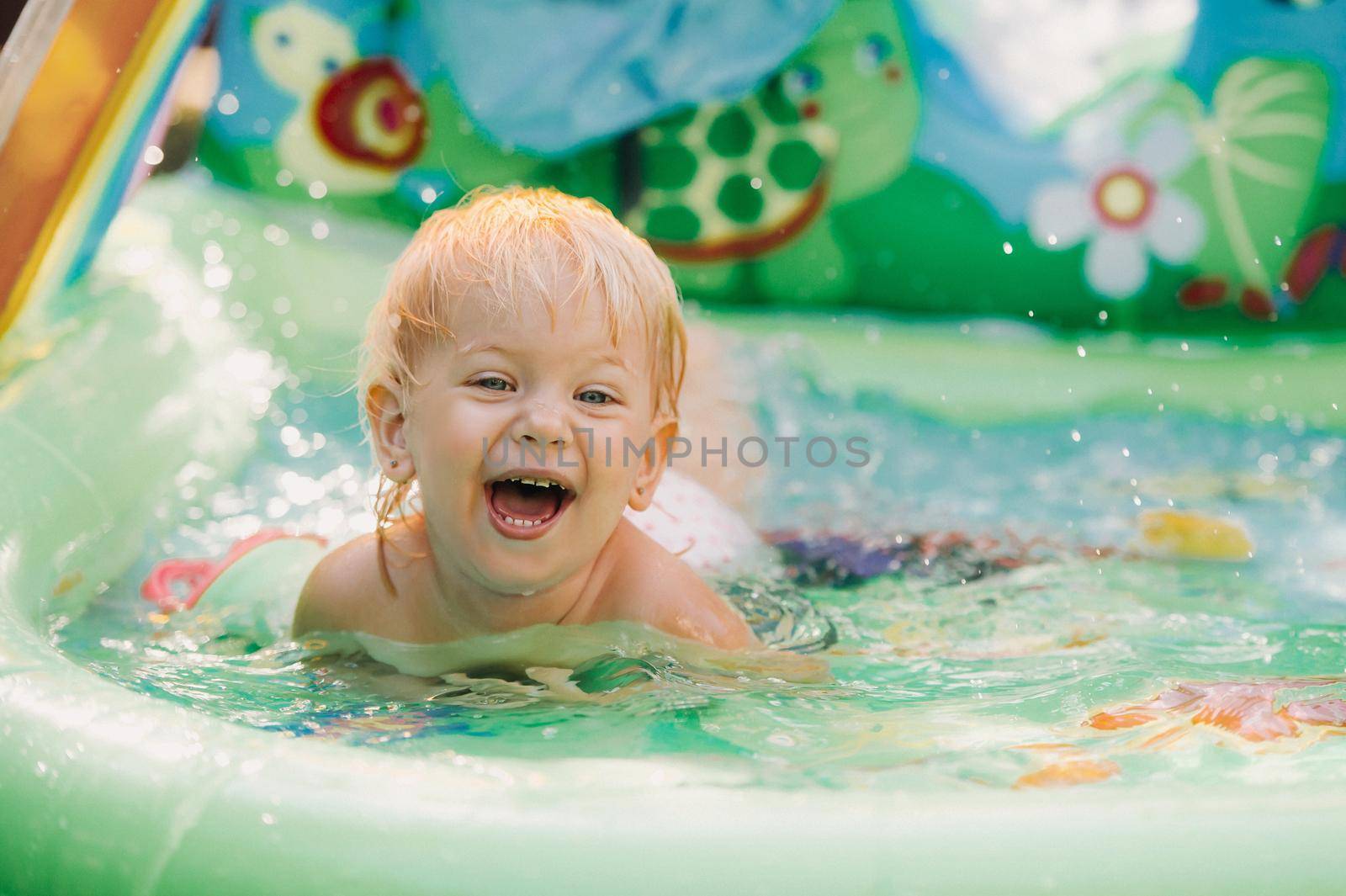 child plays in the pool. Little girl in the pool, smiling child.