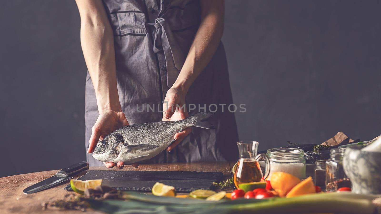 woman chef preparing fresh raw dorado fish by vvmich