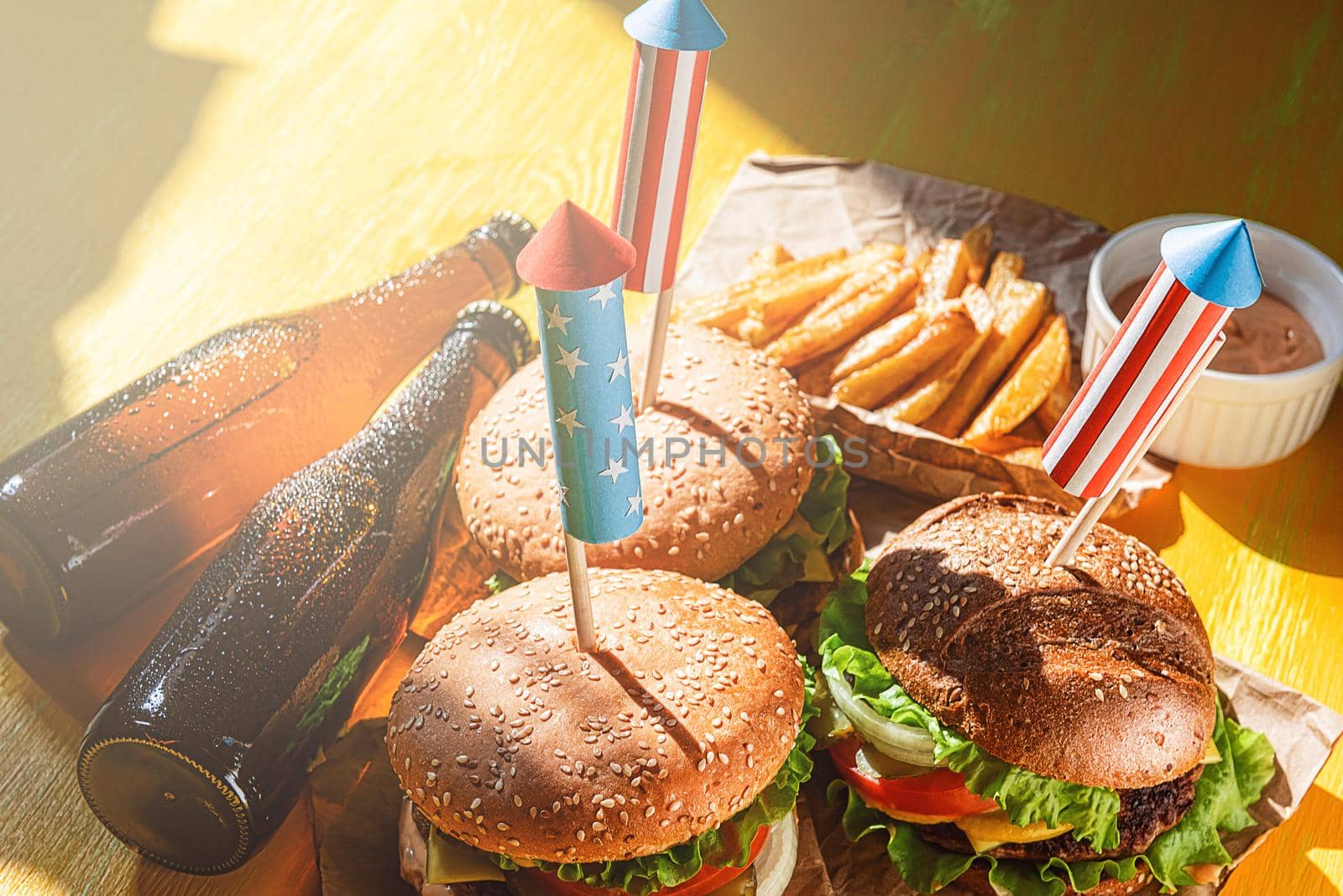 three fresh and juicy burgers with American flag-style fireworks inserted into them. barbecue concept picnic to celebrate independence day by vvmich