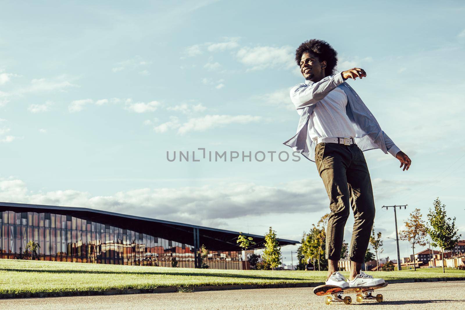 african american young man skateboarding in modern park
