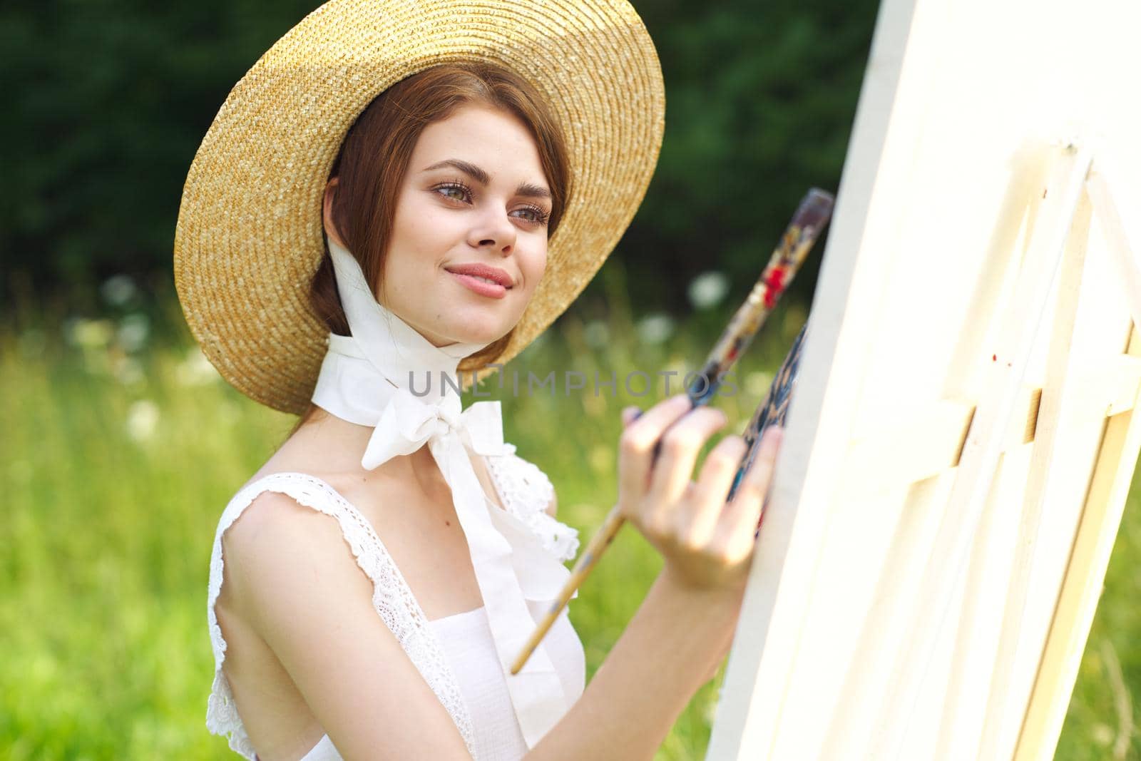 Woman in white dress artist paints on nature palette creative. High quality photo