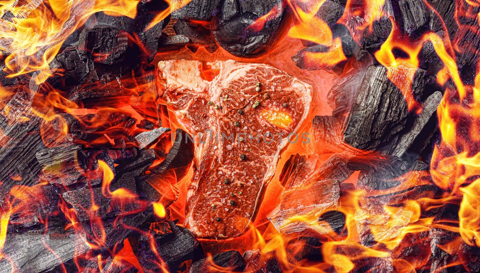 raw marbled beef steak with coals and smoke