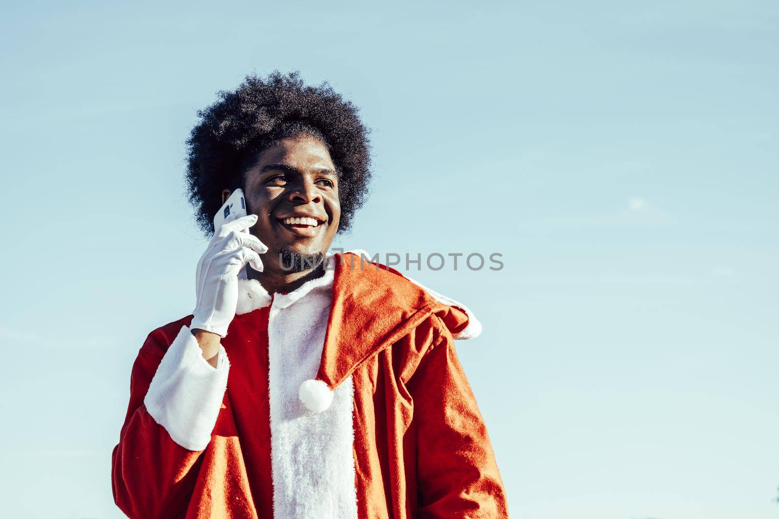 Black ethnicity afro santa claus talking on the phone outdoors