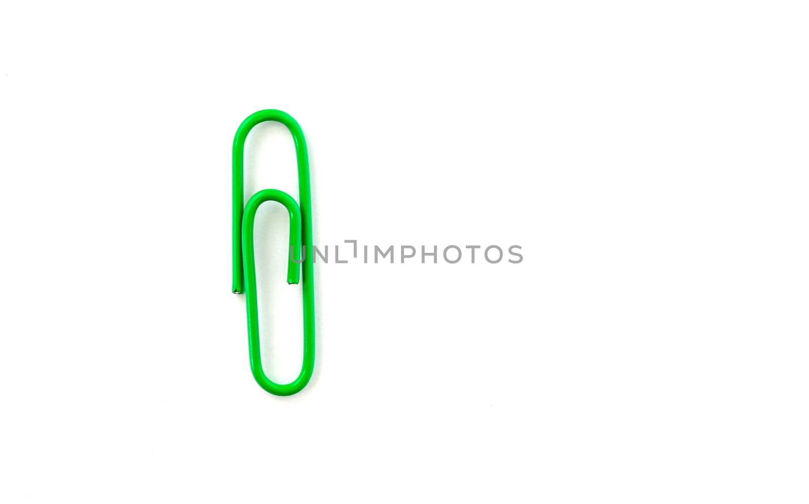 Green paper clip isolated on white background. Close up and top view