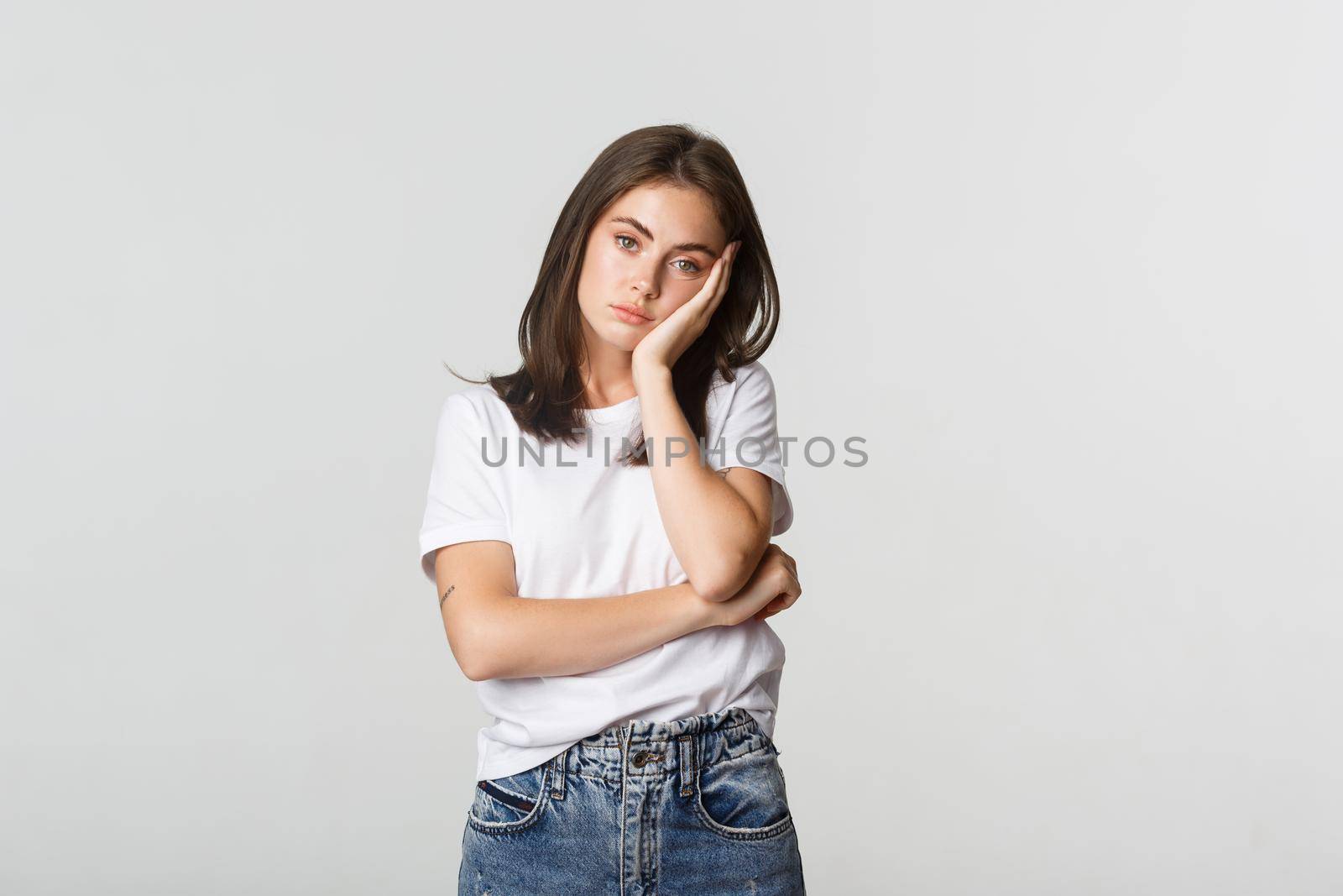Tired or annoyed young woman leaning on hand and looking indifferent.