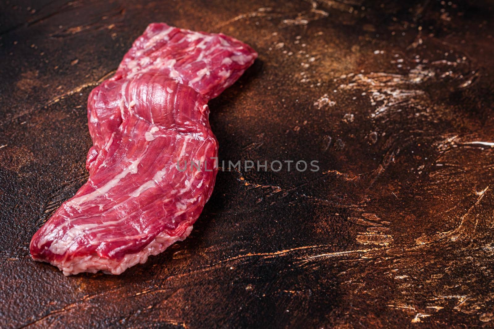 Raw machete skirt beef steak on butcher table. Dark background. Top view. Copy space.