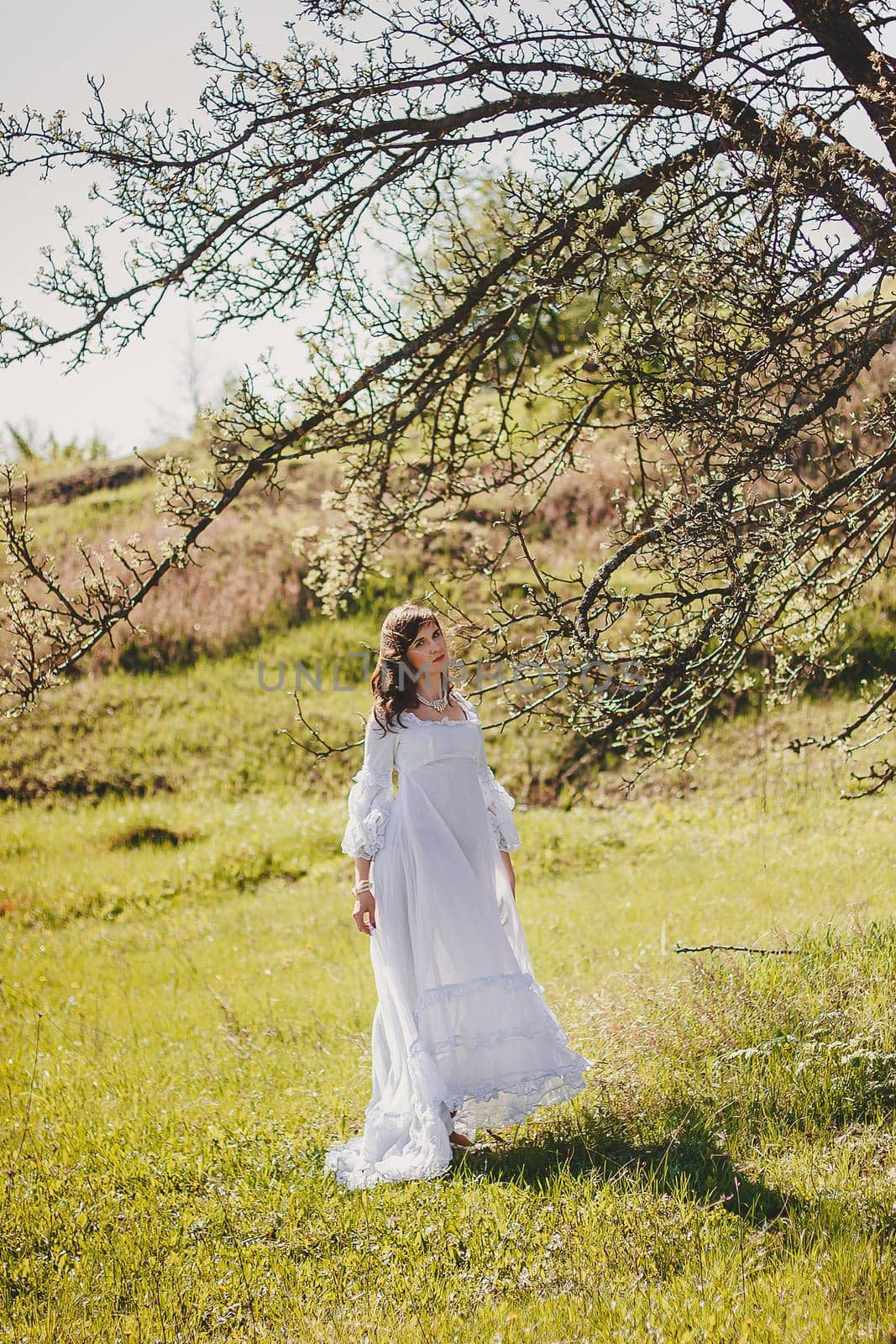 Portrait of carefree young woman in white vintage wedding style dress in spring cherry blossom garden valley by mmp1206