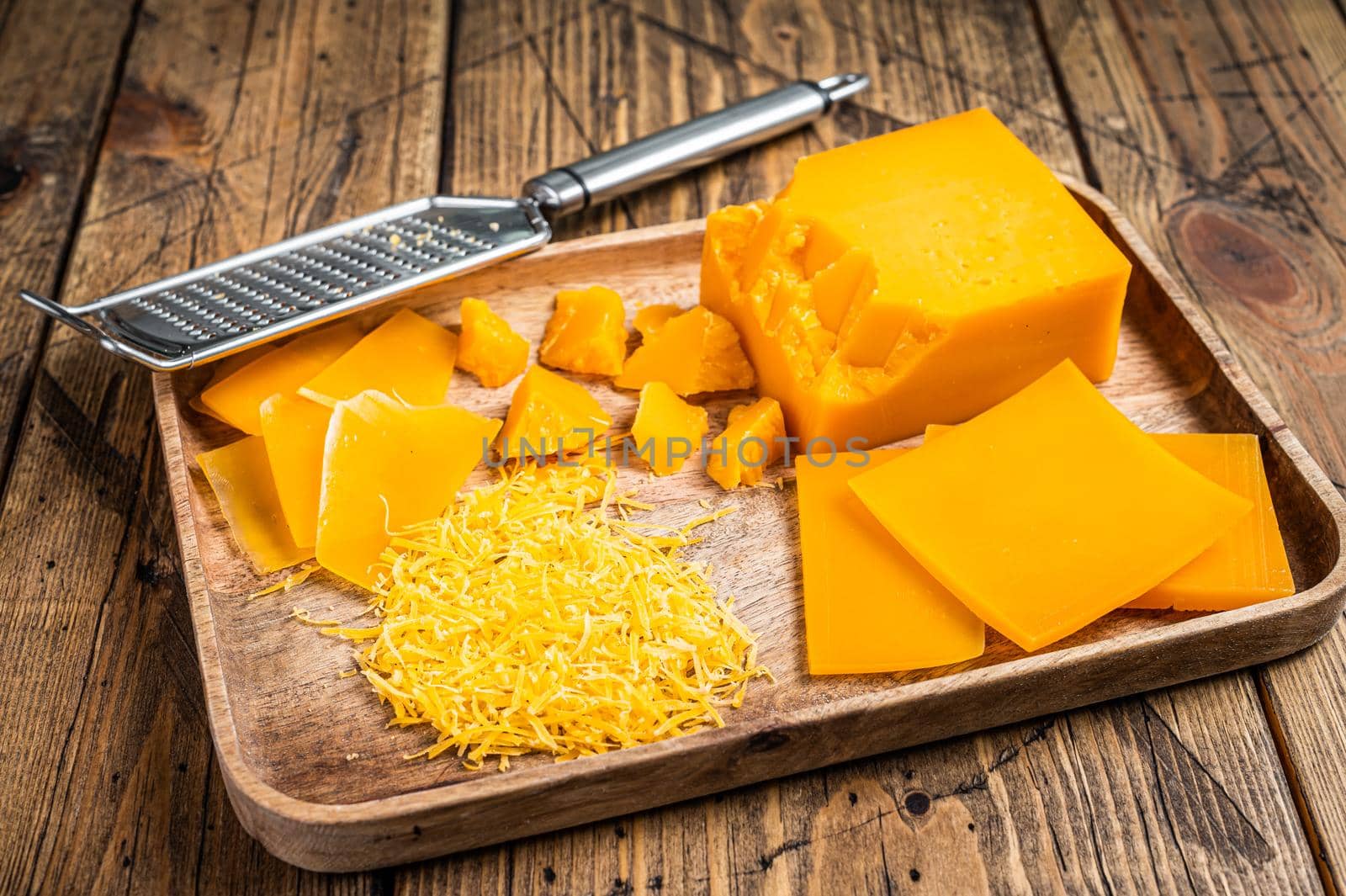 Cheddar Cheese Grated and diceded in a wooden tray. wooden background. Top view.