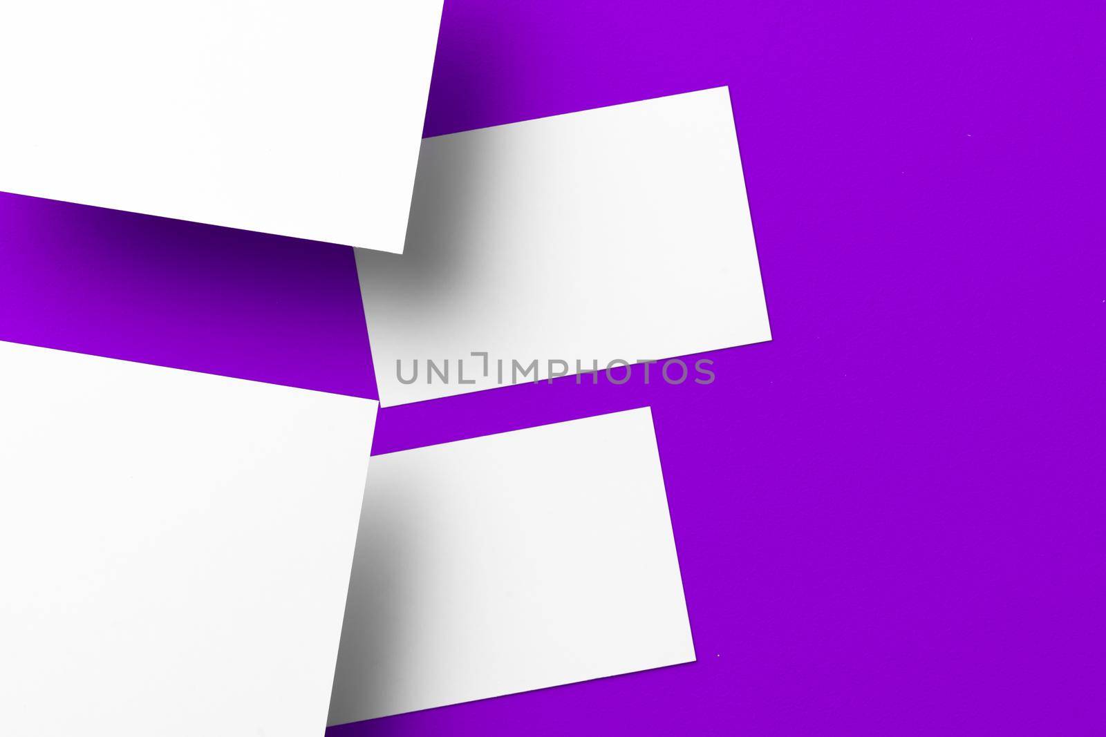 Blank white businesscards on purple background close up, copy space