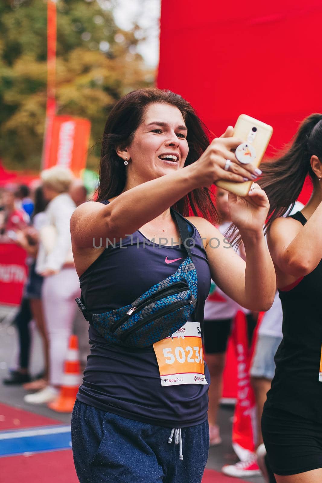 POLTAVA, UKRAINE - 1 SEPTEMBER 2019: A young woman reaches finish line and making selfie during Nova Poshta Poltava Half Marathon.
