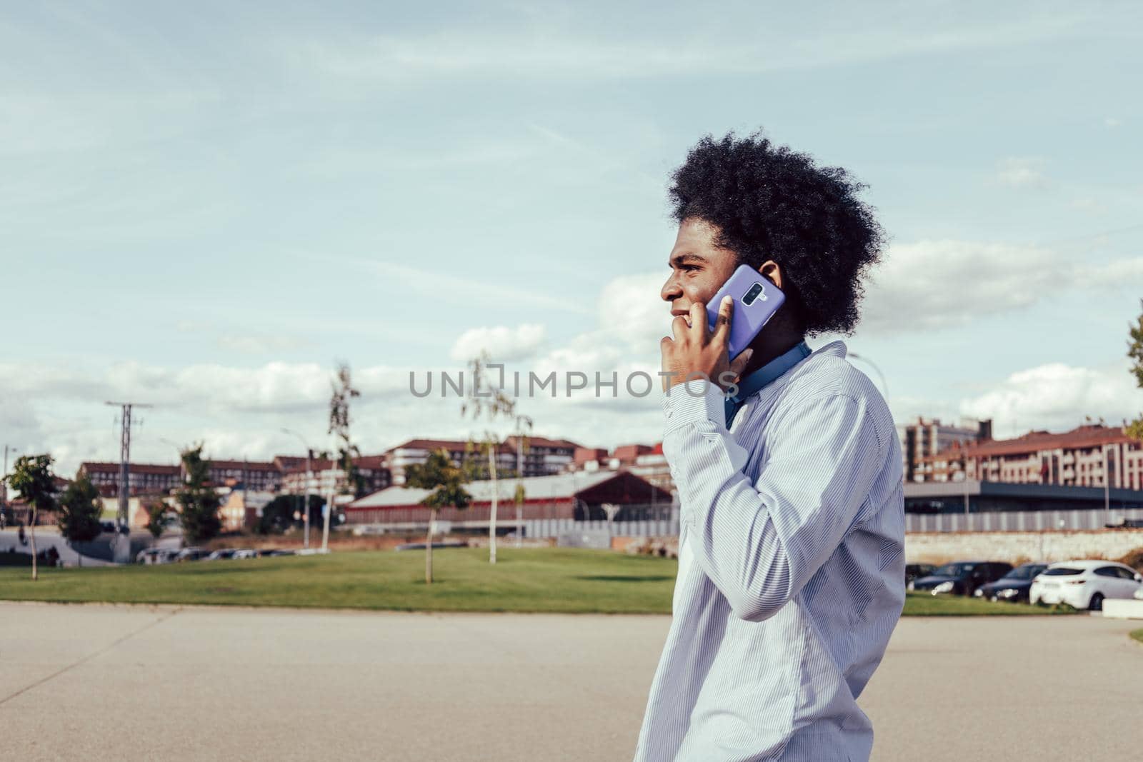 Close-up portrait of young afro man talking by phone outdoors by ALVANPH