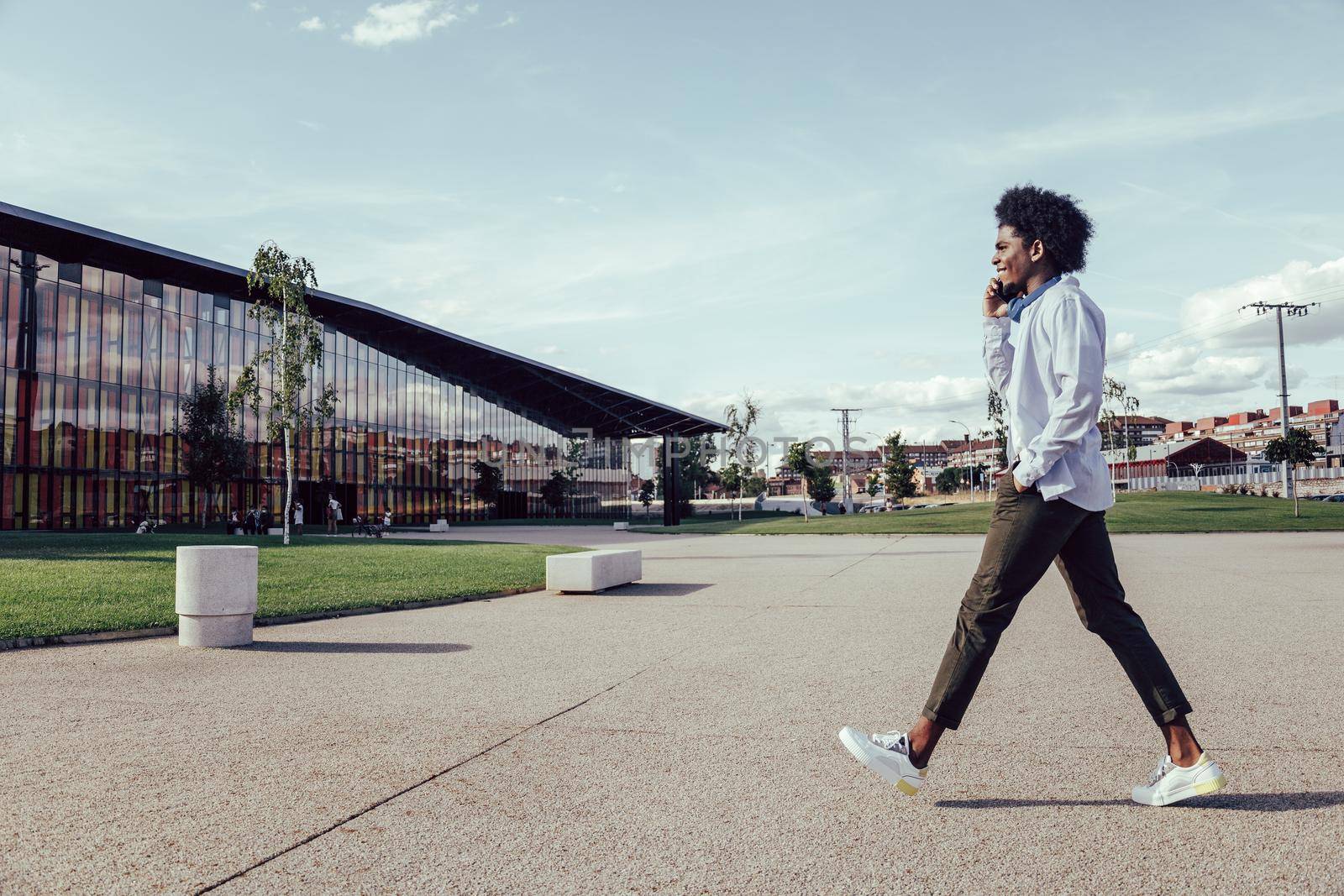 Side portrait of a young african american man walking and talking on cell phone by ALVANPH