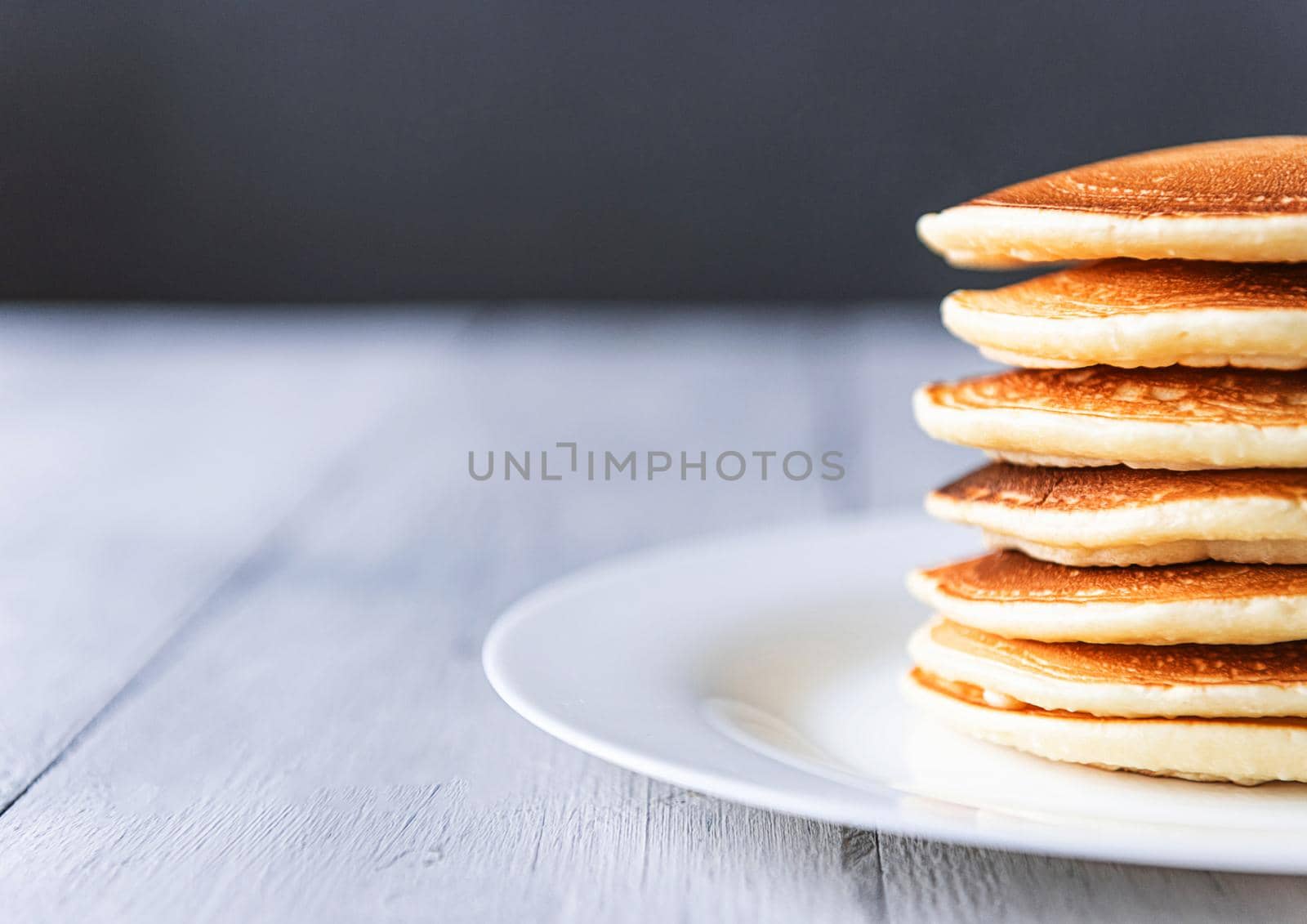fresh classic pancake stacked in stack on gray background with place for text by vvmich
