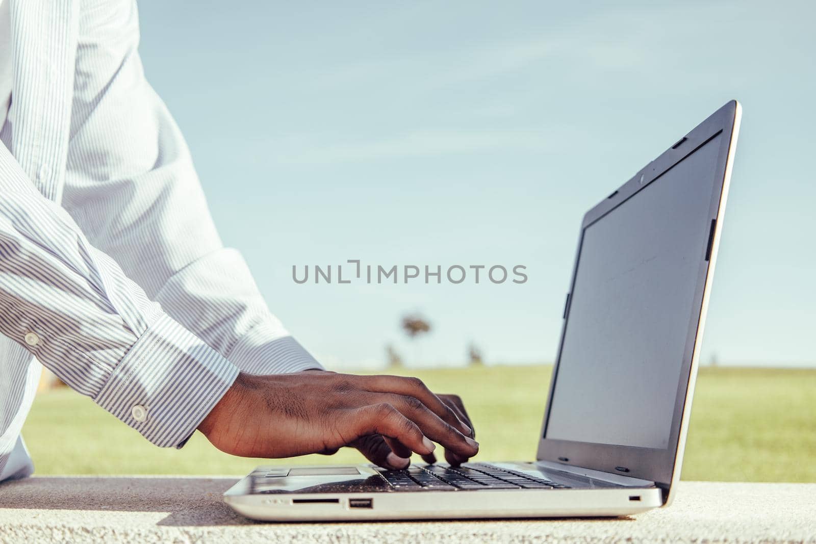 Close up of afro american hands typing on laptop on park