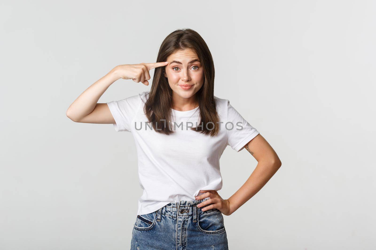 Skeptical and displeased brunette girl pointing at head, scolding someone being crazy by Benzoix