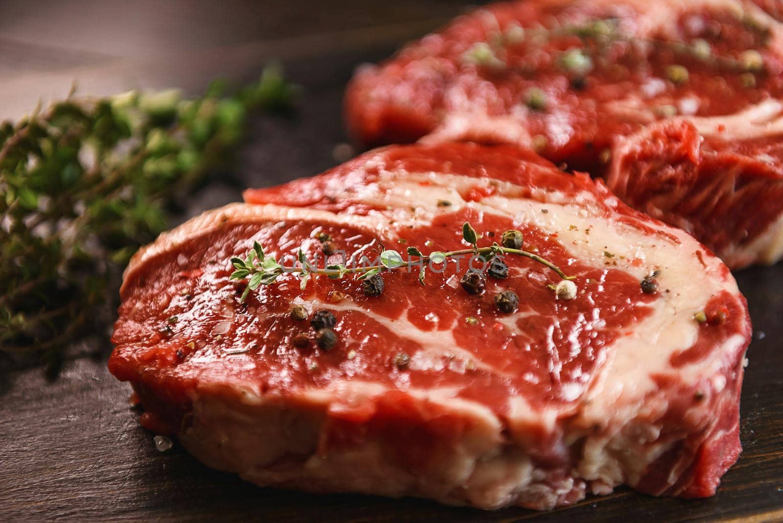 two raw marbled beef steaks in olive oil and spices ready for frying. dinner party concept