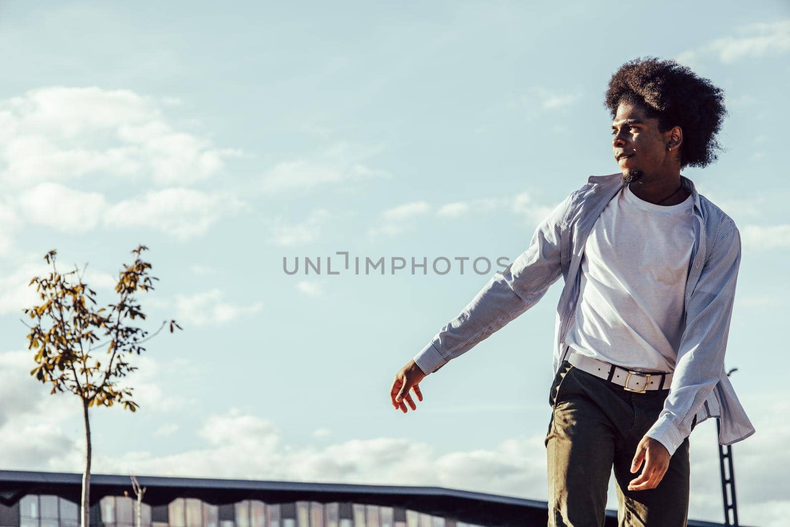 Close up view of african american young man skateboarding over sky background by ALVANPH