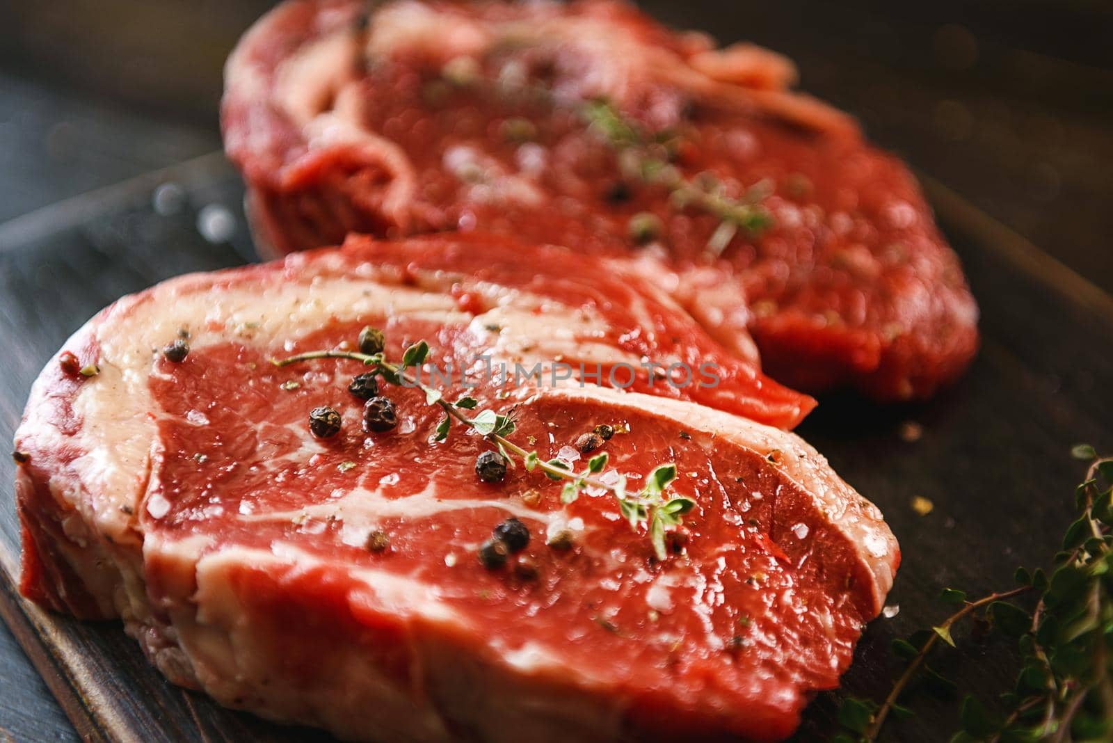 two raw marbled beef steaks in olive oil and spices ready for frying. dinner party concept