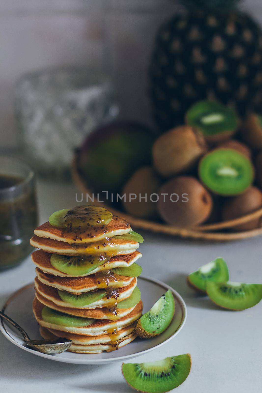 Plate of pancakes dripping with kiwi jam with kiwi pieces. Shrovetide Maslenitsa Butter Week festival meal. Shrove Tuesday. Pancake day