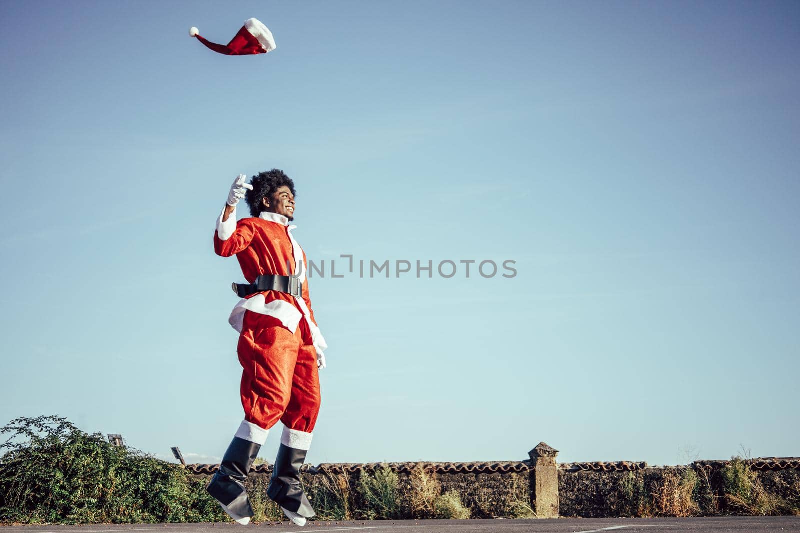 Colombian ethnicity santa claus jumping over sky background, copy space