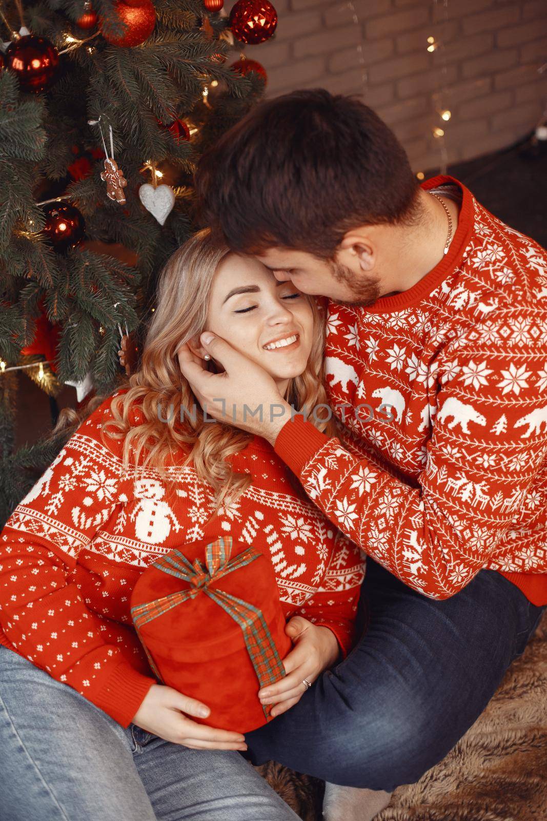 Cute couple sitting at home near christmas tree by prostooleh