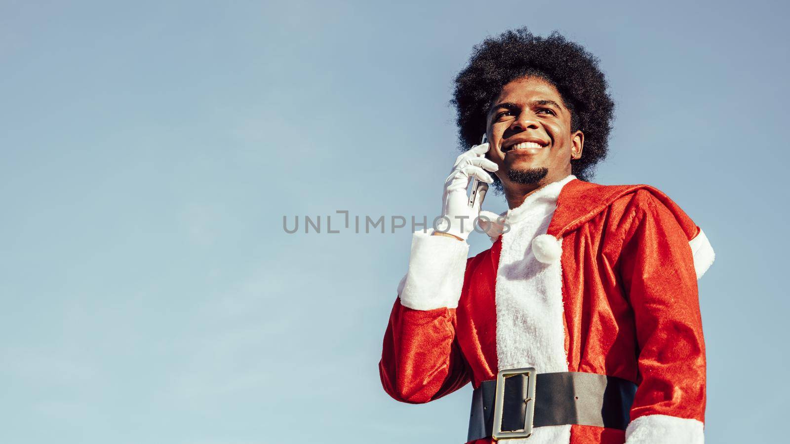 Close-up portrait of black ethnicity afro santa talking on the phone by ALVANPH