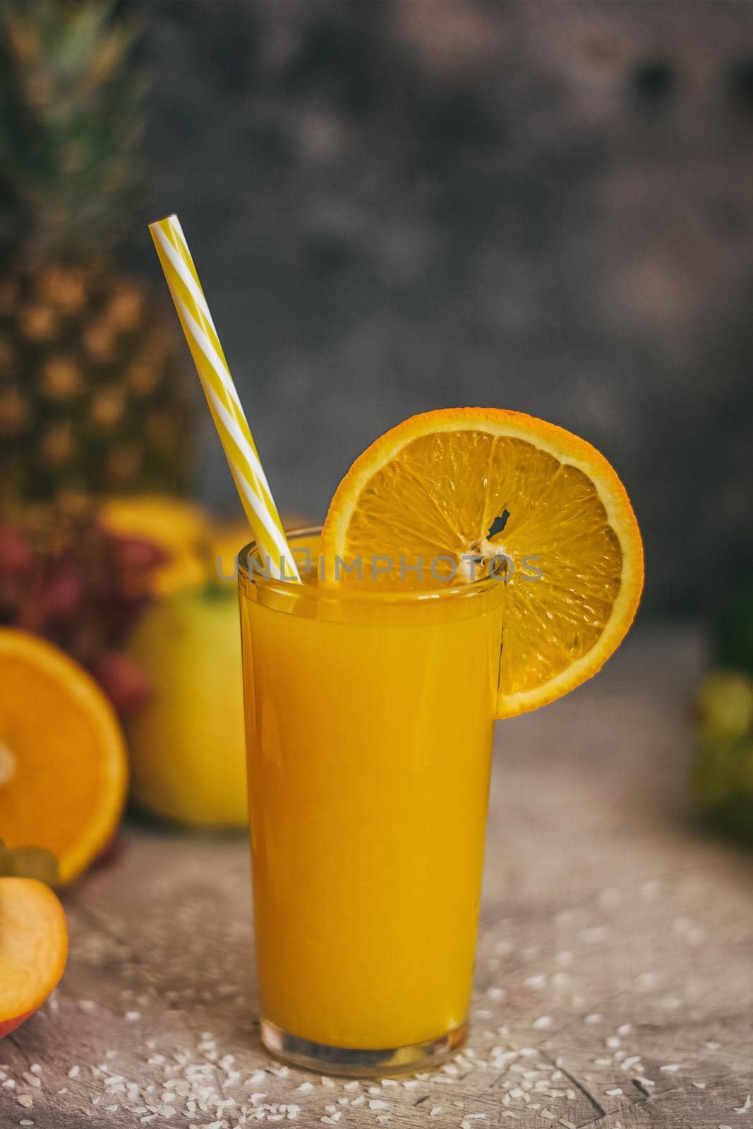 Composition with a glass of orange juice and tropical fruits.