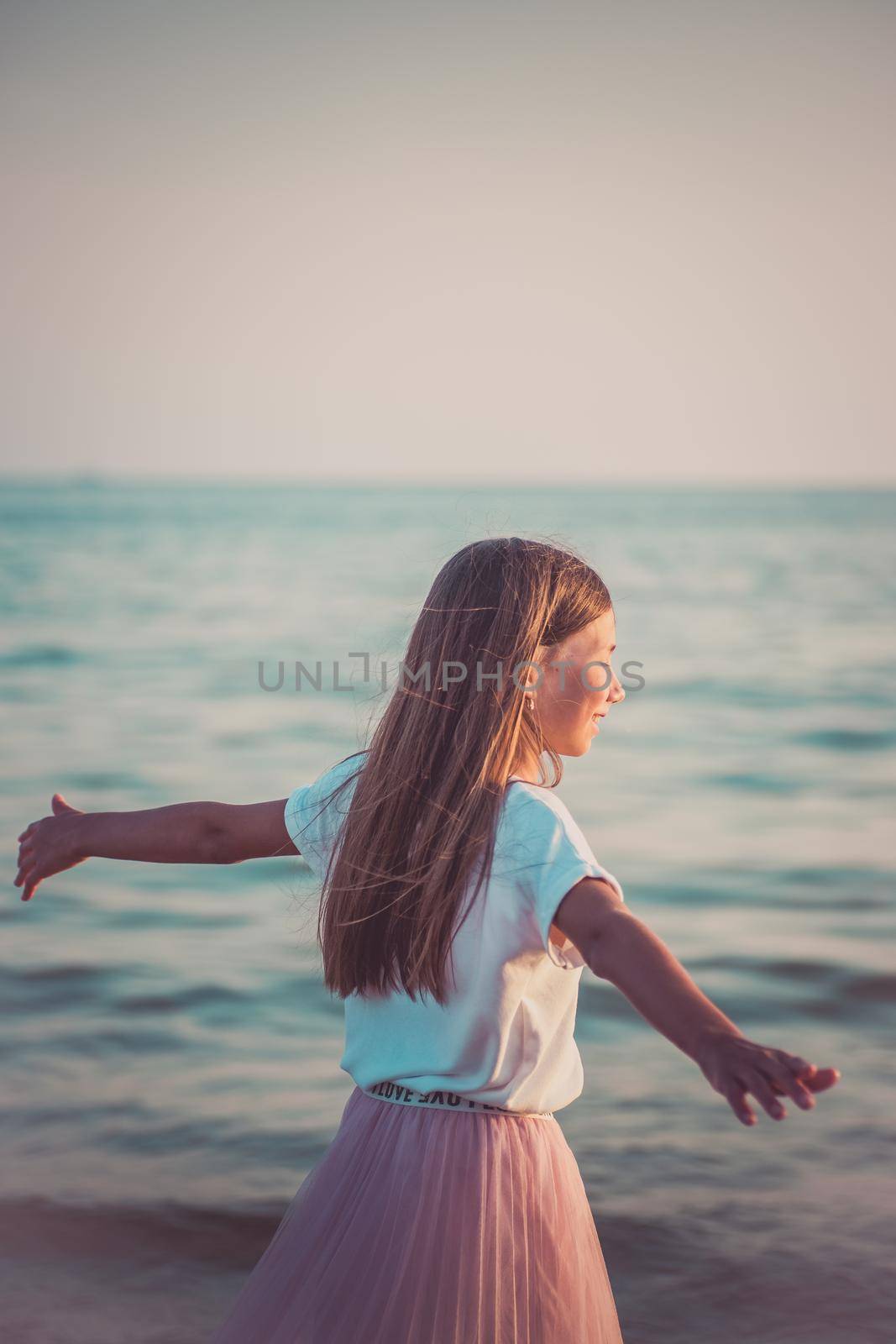 Happy little girl is spinning and dancing on the beach on a Sunny day. by alf061
