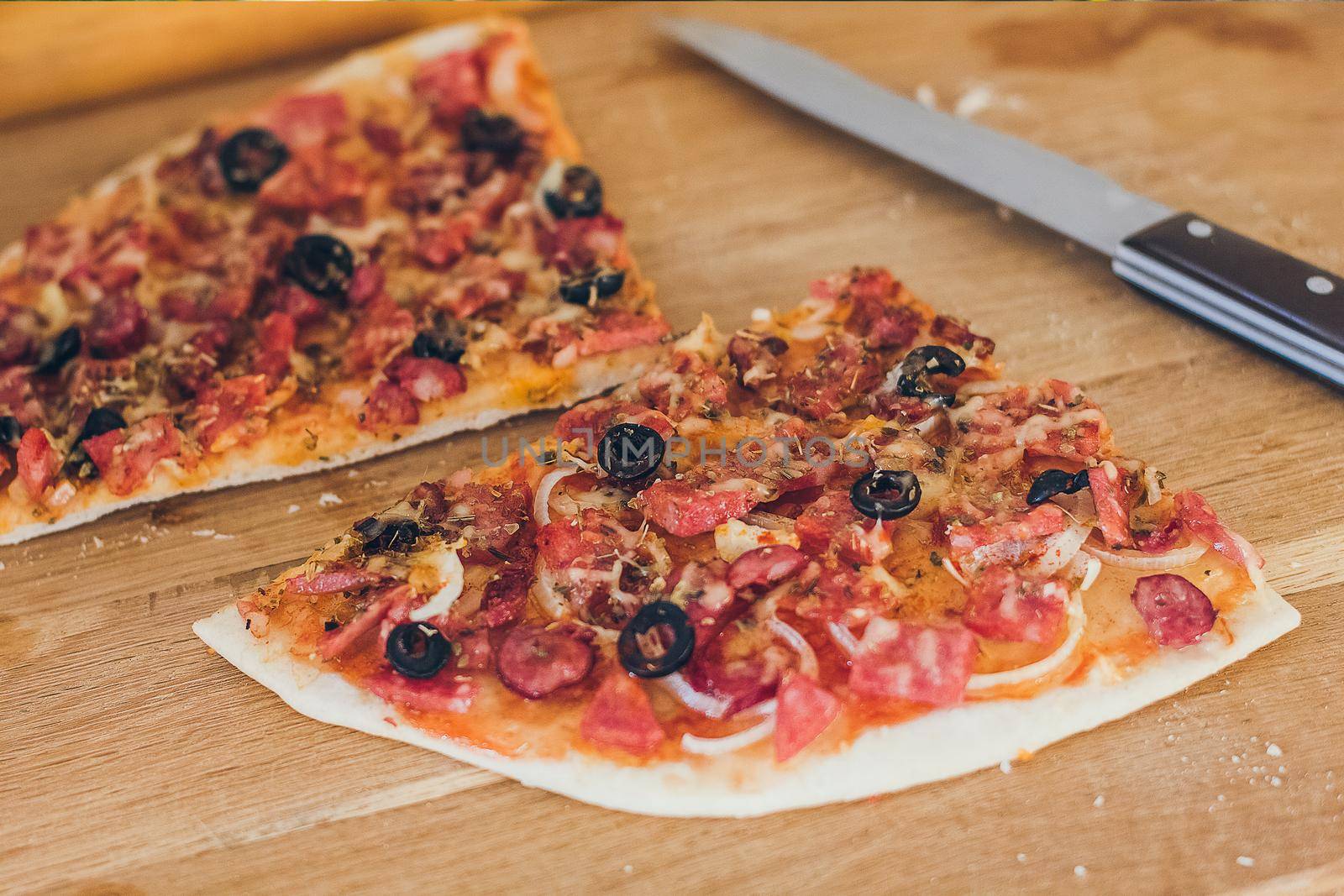 Fresh pizza with olives, cheese and bacon on kitchen table closeup