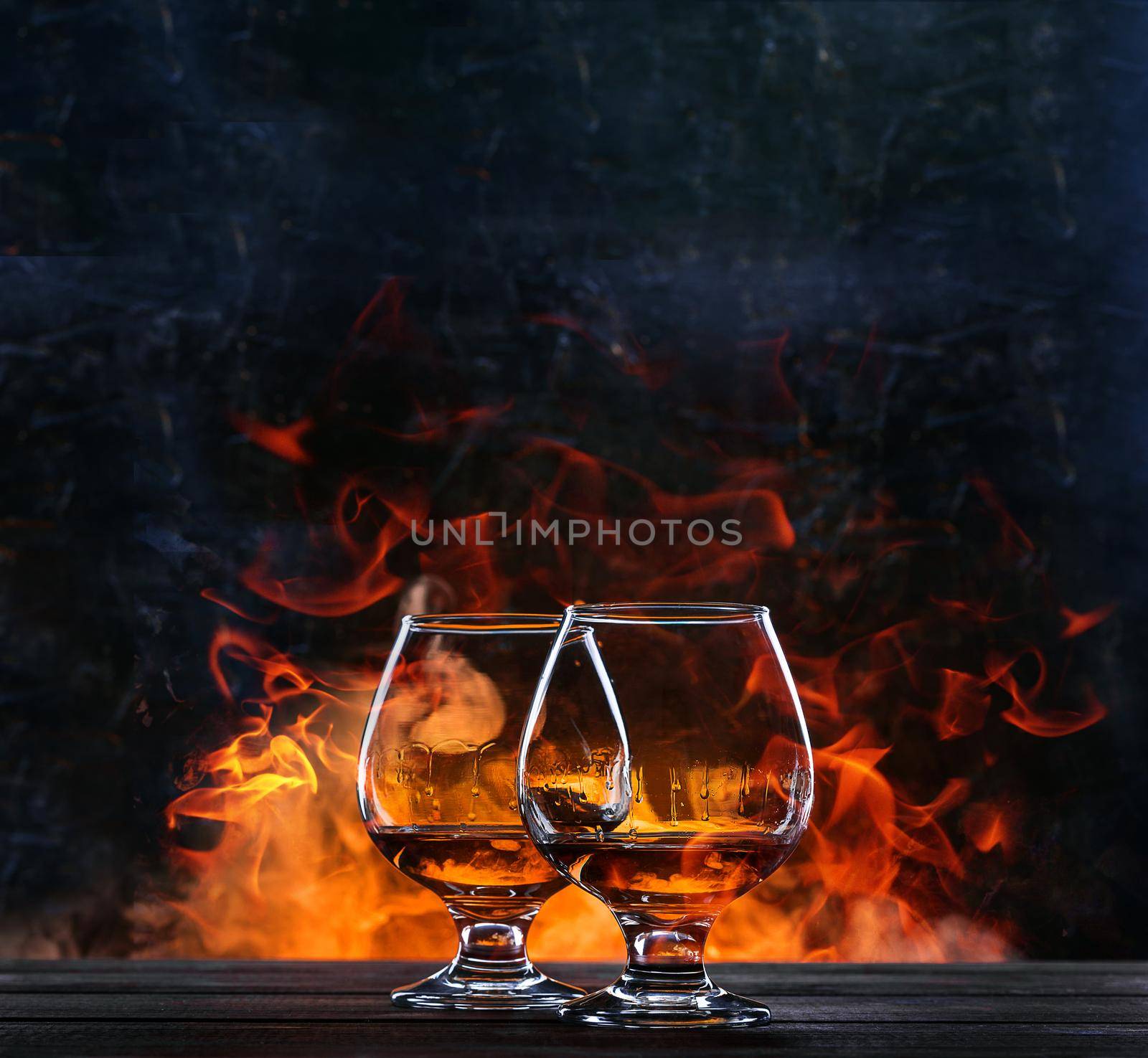 French brandy in a classic glass on the background of fire for two. concept of unhurried evening talk of two friends over a glass of brandy