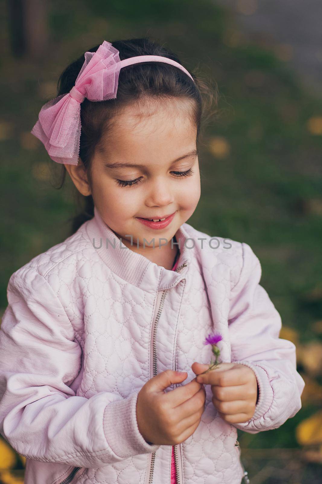 Young girl in a pink jacket and pink leggings in the park.