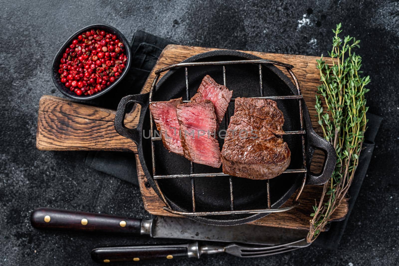 Grilled fillet mignon beef steak on a grill. Black background. Top view.