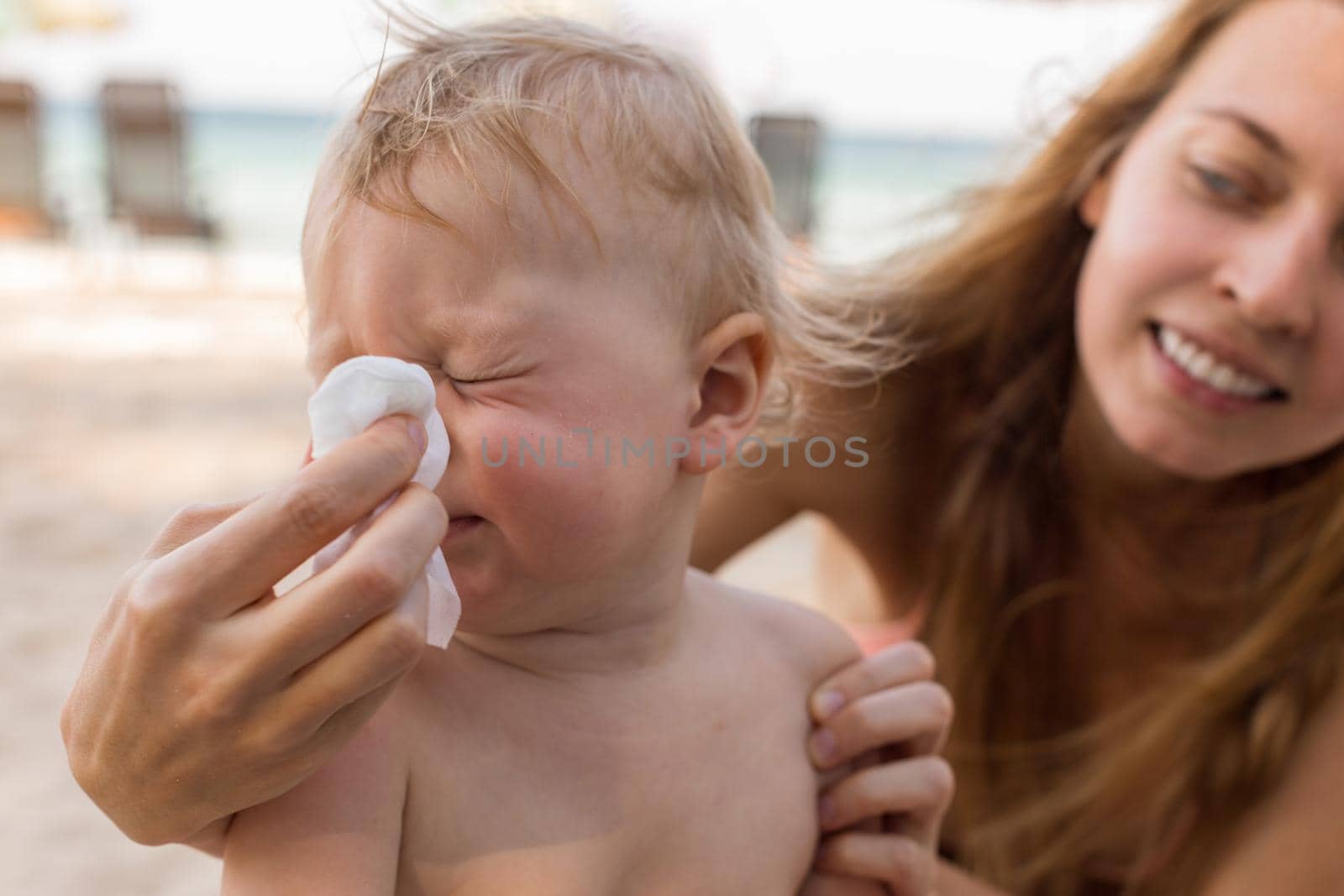 Mother helping baby to blow nose by Demkat