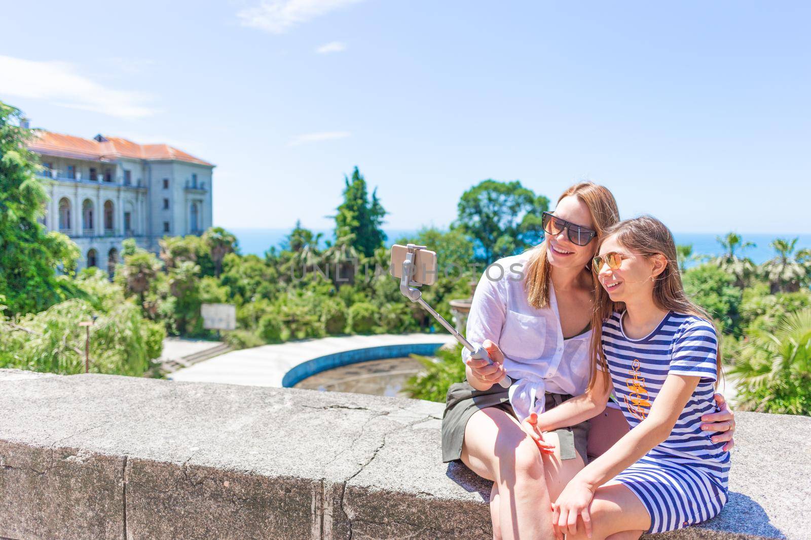 Happy family mother and her adorable little daughter on summer vacation taking selfie with smartphone.