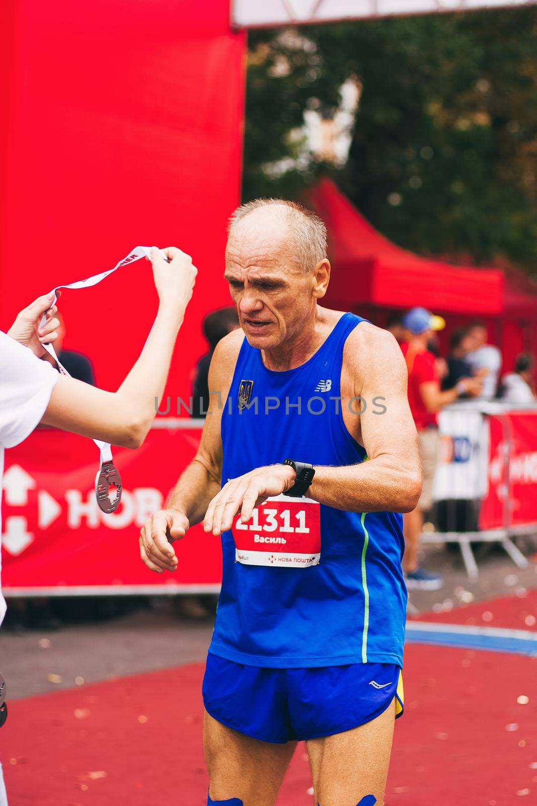 POLTAVA, UKRAINE - 1 SEPTEMBER 2019: A mature seniour man reaches finish line during Nova Poshta Poltava Half Marathon by mmp1206