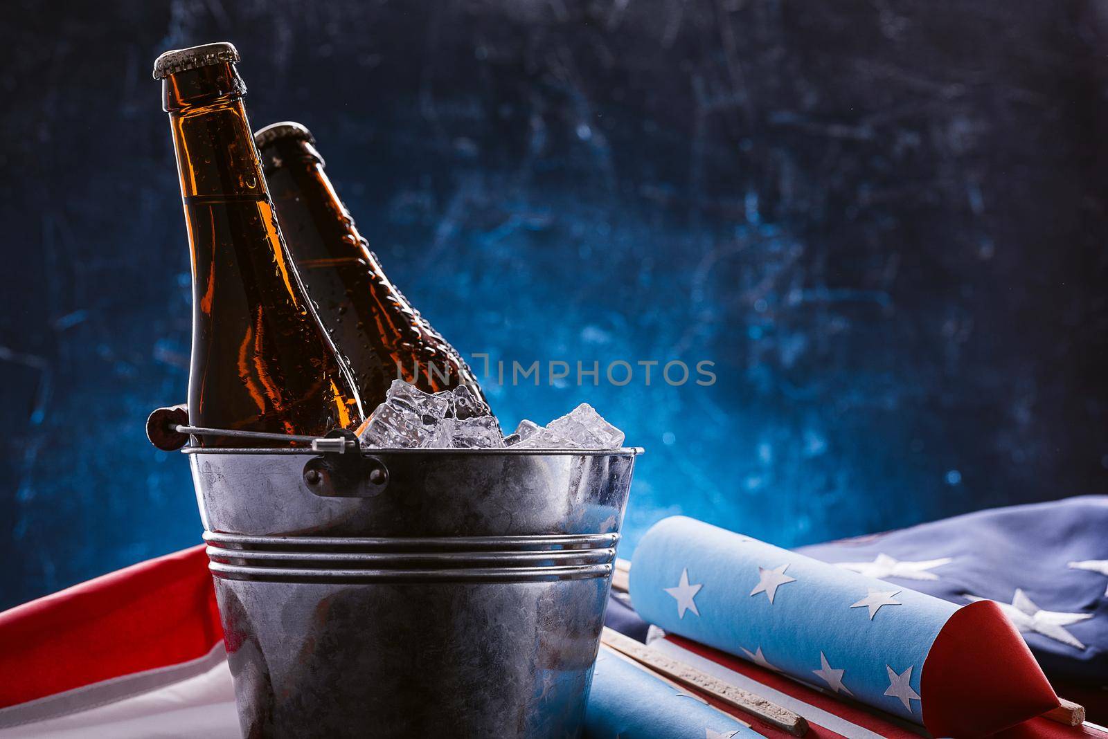 two bottles of beer in an ice bucket with the American flag lying nearby and rockets for fireworks. Independence Day celebration concept by vvmich