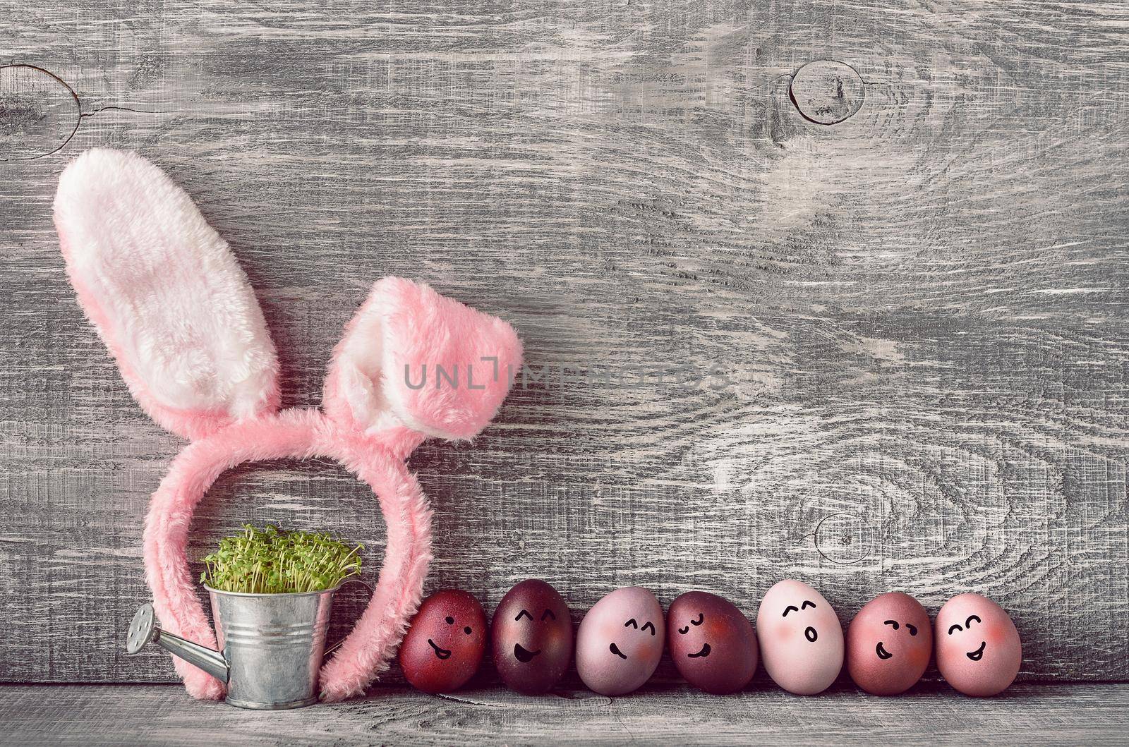 Easter eggs in a fashionable coloring on a gray wooden background with a female hoop with Easter bunny ears by vvmich
